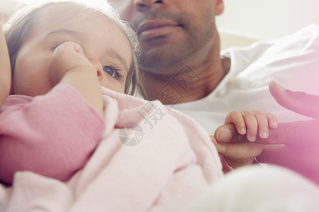 婴儿女在父亲的膝上用安慰毯子舔拇指图片