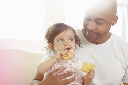女婴和父亲在沙发上吃零食图片