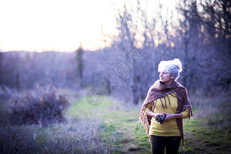 黄昏时在林地漫步的白头发老奶奶图片