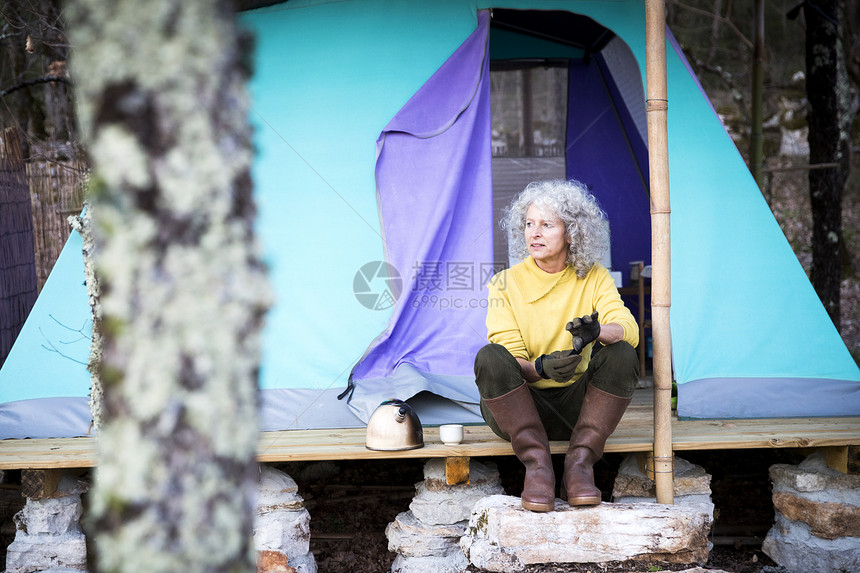 坐在林地露营门廊上的白头发老奶奶图片