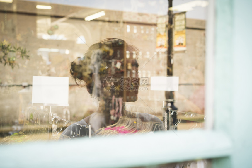 妇女在商店窗口中的反射图片