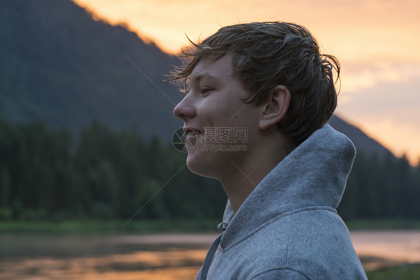 美国华盛顿日落时沿河流对十几岁男孩的肖像图片