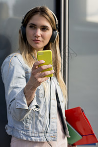 年轻女户外戴耳机用智能手自拍图片