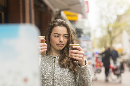 在市场摊位上挑选储藏罐的年轻女性图片