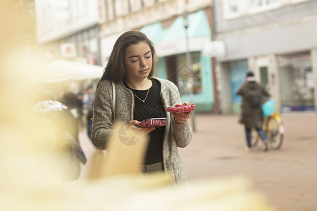 在市场摊位上的挑选水果的年轻女性图片