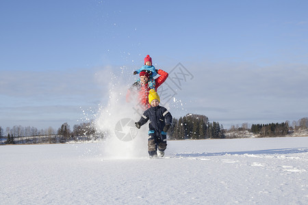 父亲和两个孩子在雪地里玩耍图片