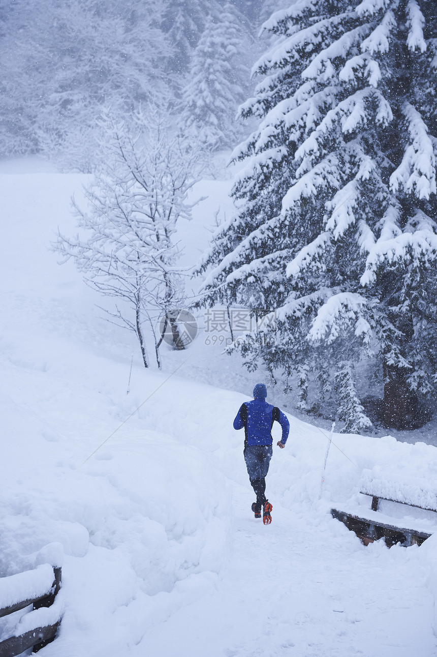 在瑞士Gstaad的深雪中奔向正轨的男跑步者后视景瑞士Gstaad图片