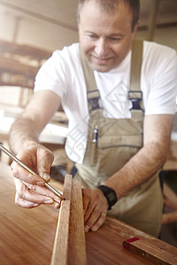 男木匠在工作场所用铅笔在木材上打标记图片