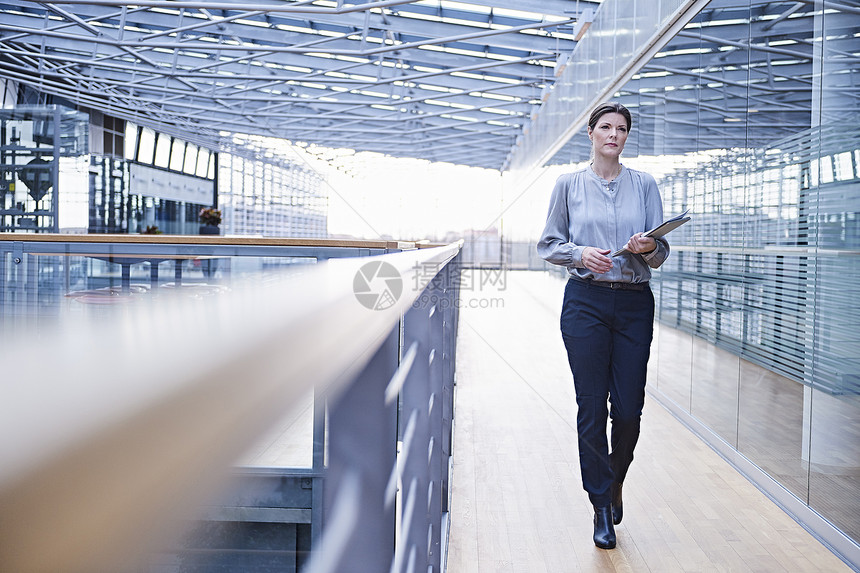商业妇女沿着办公室阳台行走图片