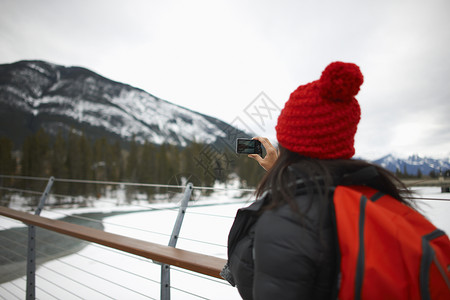 用手机拍雪山照片的女人·图片