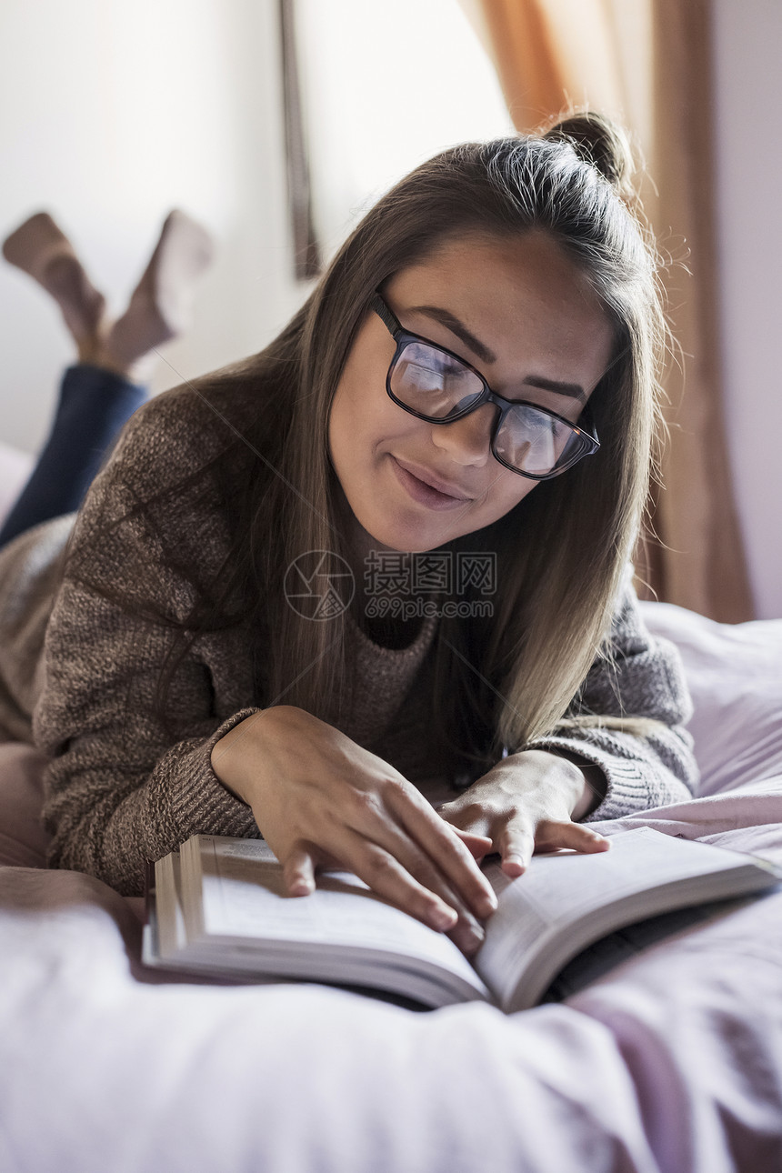 年轻女士在床上读书图片