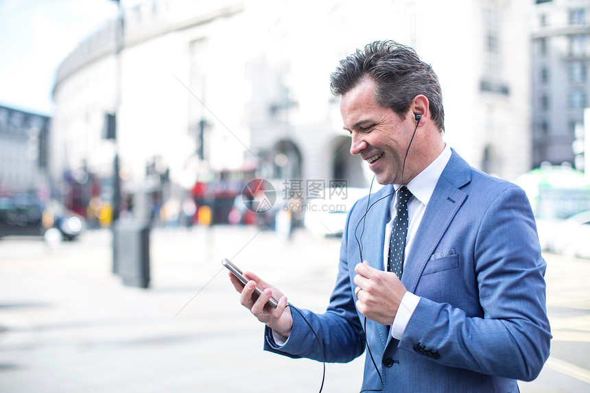 联合王国伦敦拥有智能手机和耳机的街头商人图片