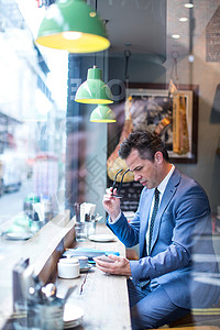 餐厅窗口座位上看智能手机的商人图片