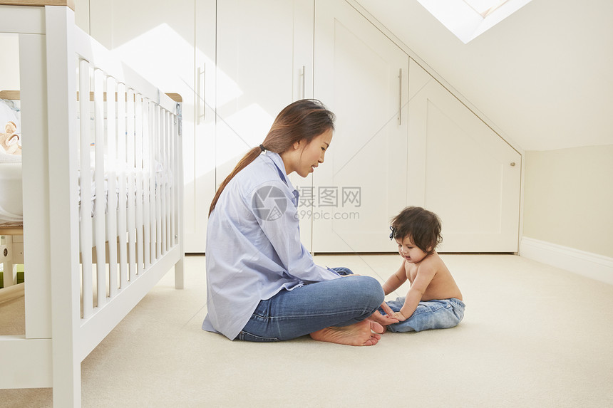 坐在地板上与女婴玩耍的妇女图片