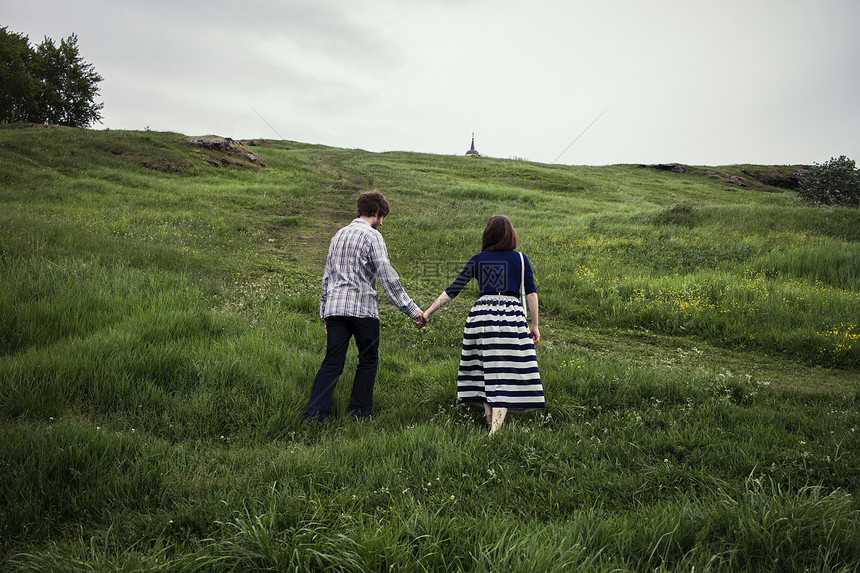 一对夫妇走在草地山上手牵手图片