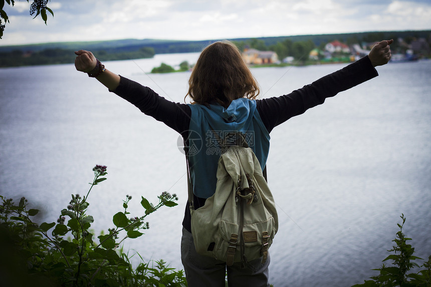 一名女子举着双臂看向湖面图片