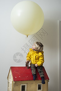 男孩坐在屋上看着气球图片