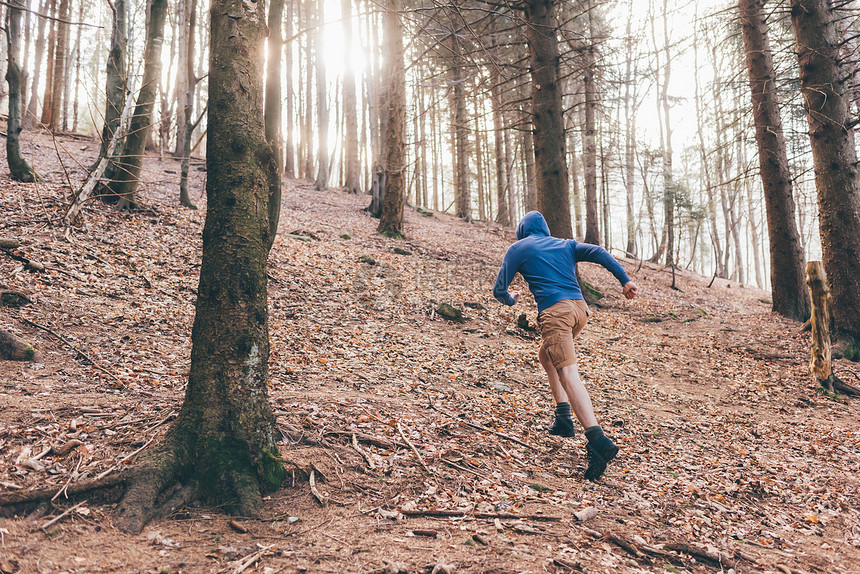 森林陡坡上跑步的男人背影图片
