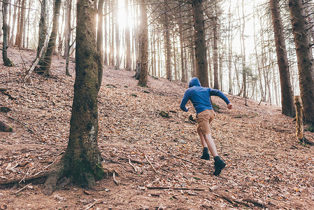 森林陡坡上跑步的男人背影图片