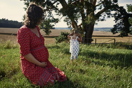 坐在田里看着女儿的孕妇高清图片