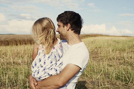 抱着女儿的夫亲在小麦田外望着高清图片