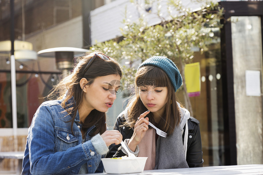两名年轻妇女在市场野餐席吃食物图片
