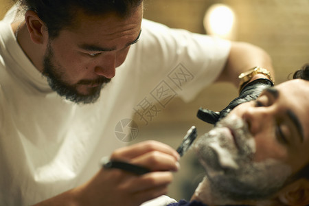 理发店的师给客户湿刮胡子图片