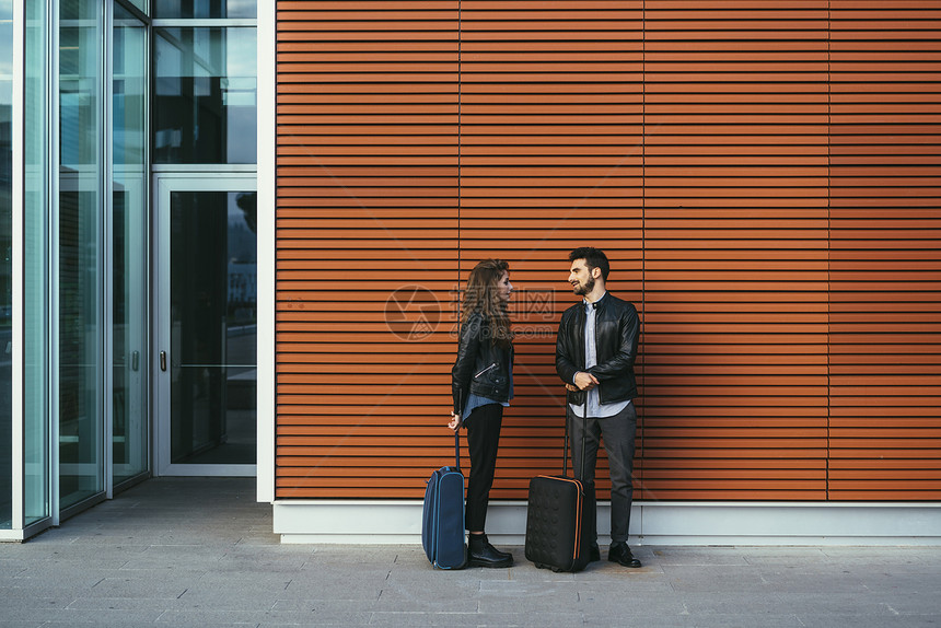 意大利佛罗伦萨拿着行李站在橙色墙边的夫妇图片