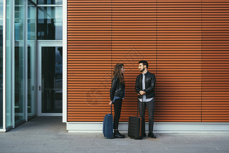 意大利佛罗伦萨拿着行李站在橙色墙边的夫妇图片