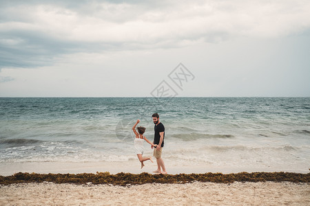 父亲和女儿在墨西哥坎昆海滩玩耍背景图片