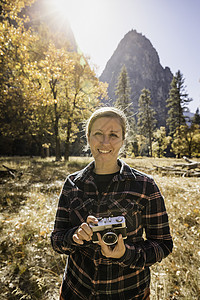 美国加利福尼亚州Yosemite公园中拿着相机的妇女的秋季肖像图片