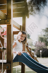阿雷佐年轻女孩坐在公园滑梯的顶端微笑背景