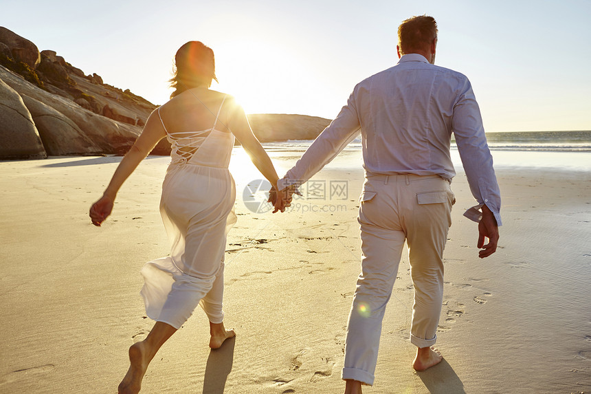 在海滩上手牵手行走的夫妇图片