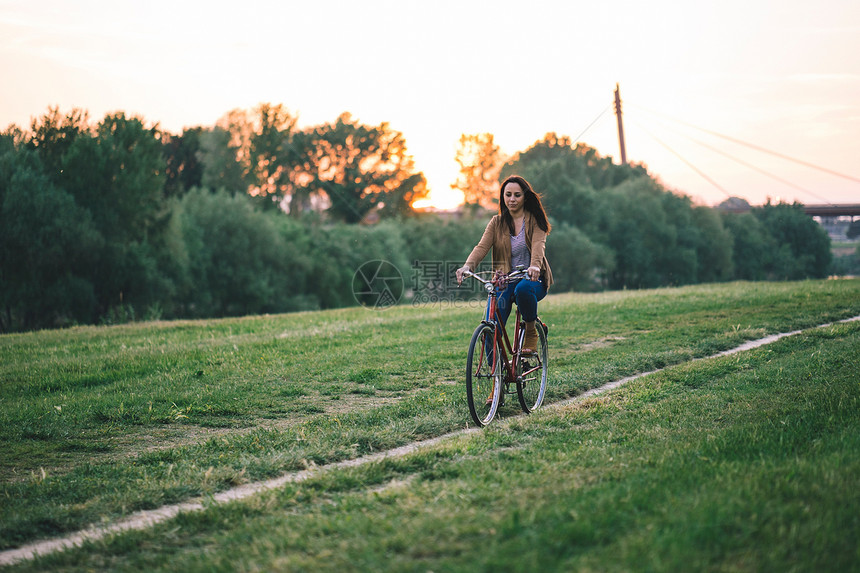 在草地上骑自行车的妇女图片