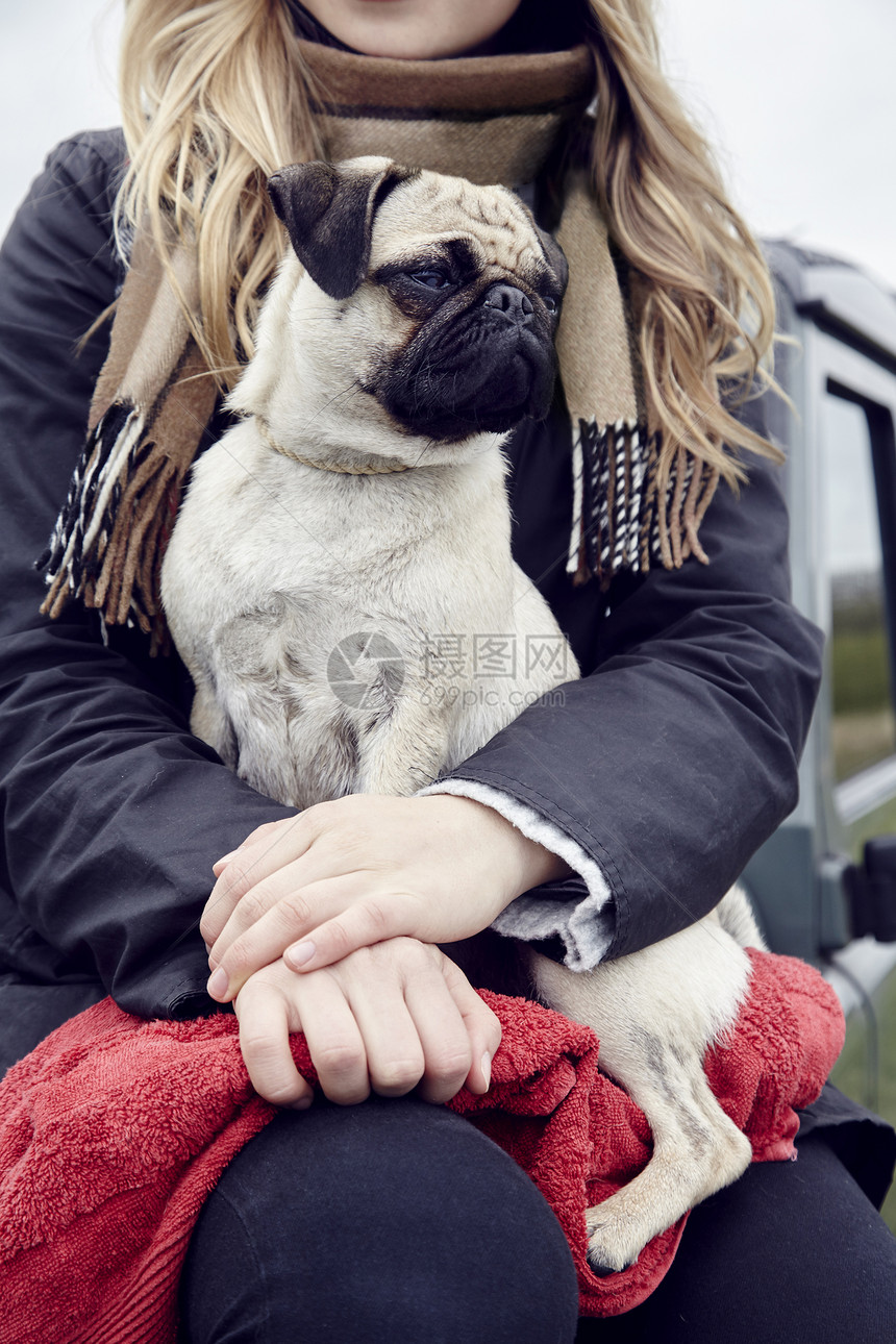 坐在车上抱着狗的年轻妇女图片