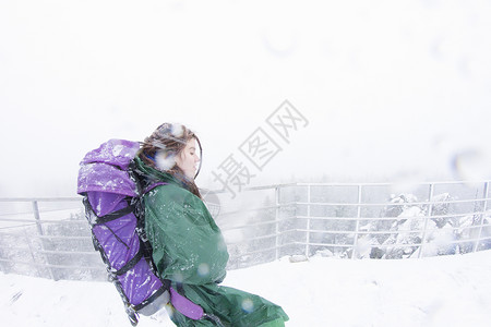 尼兹尼塔吉尔在雪暴中走在山上女徒步旅行者侧身背景