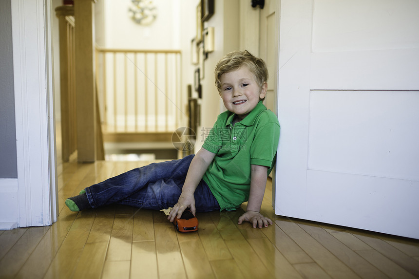 男孩坐在地板上玩玩具车图片
