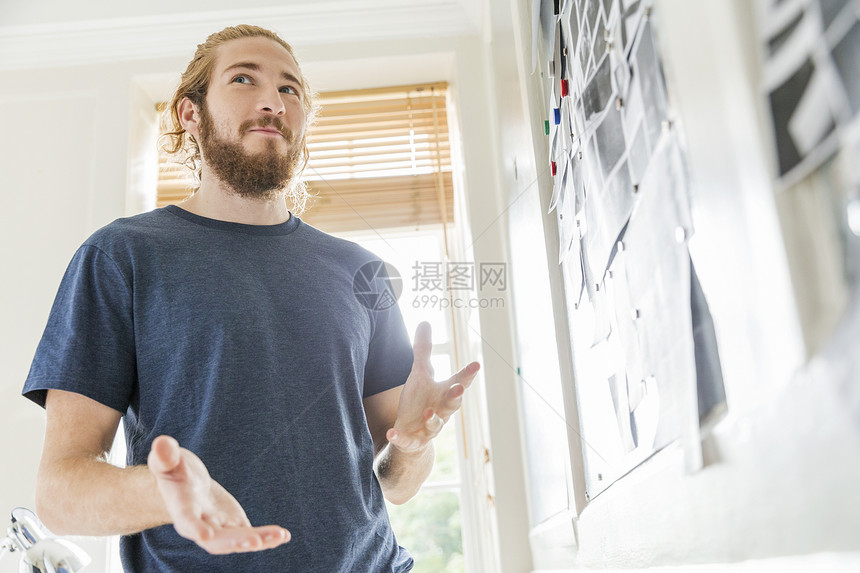 年轻男设计师在创意工作室情绪板前沉思图片