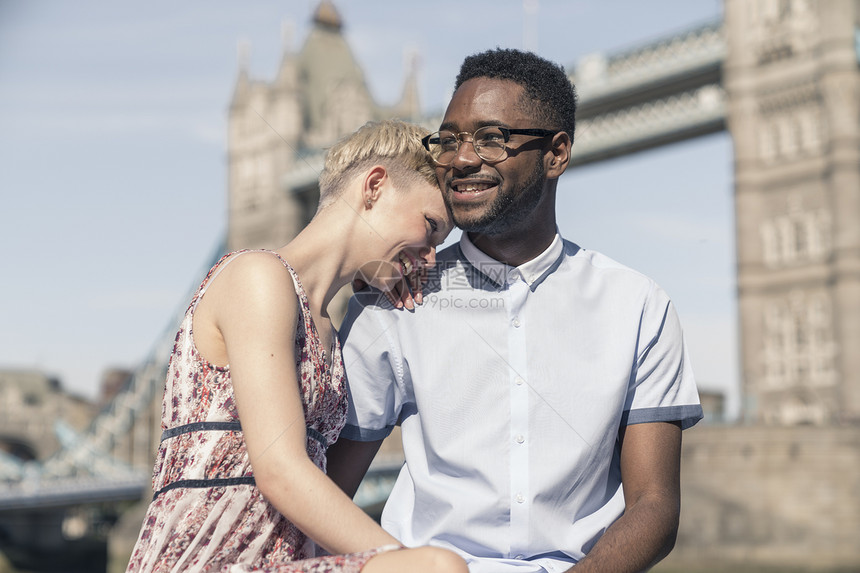 坐在伦敦桥前微笑的年轻夫妇图片