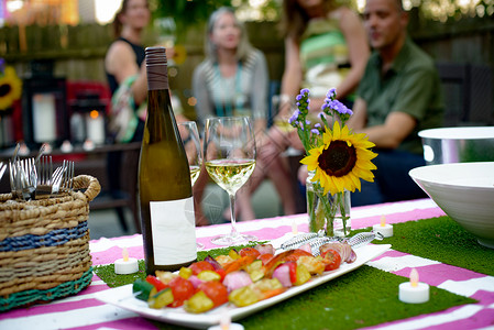 园艺晚会上的一群人露天酒瓶和蔬菜烤肉串图片