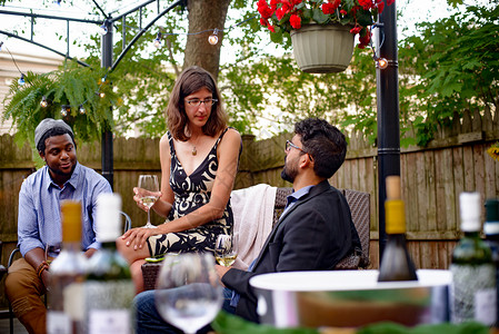 三个人在花园派对上坐着聊天拿葡萄酒杯图片
