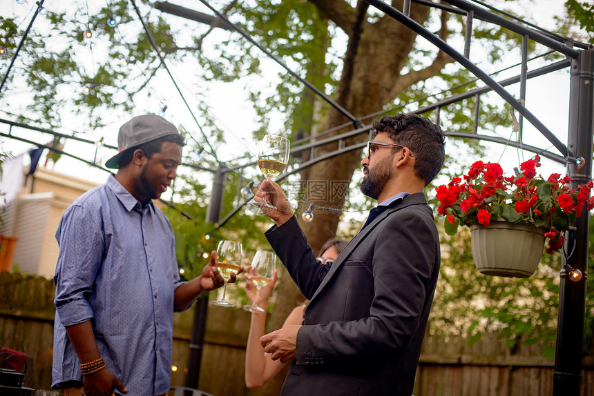 三个人在花园派对上拿着葡萄酒杯图片