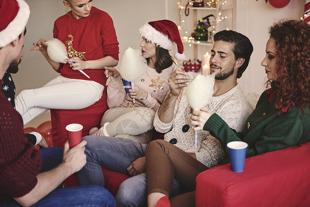 在圣诞节派对上吃沙发糖果的男女青年图片