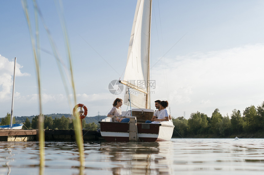 三个朋友在湖边的帆船上放松图片