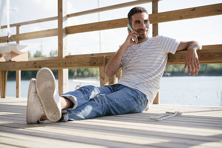 男人放松的坐在码头打电话图片