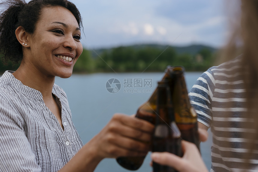 三个朋友在湖边举着啤酒瓶庆祝图片