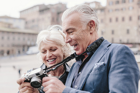 意大利托斯卡纳省锡耶市广场看数码相机的旅游夫妇图片