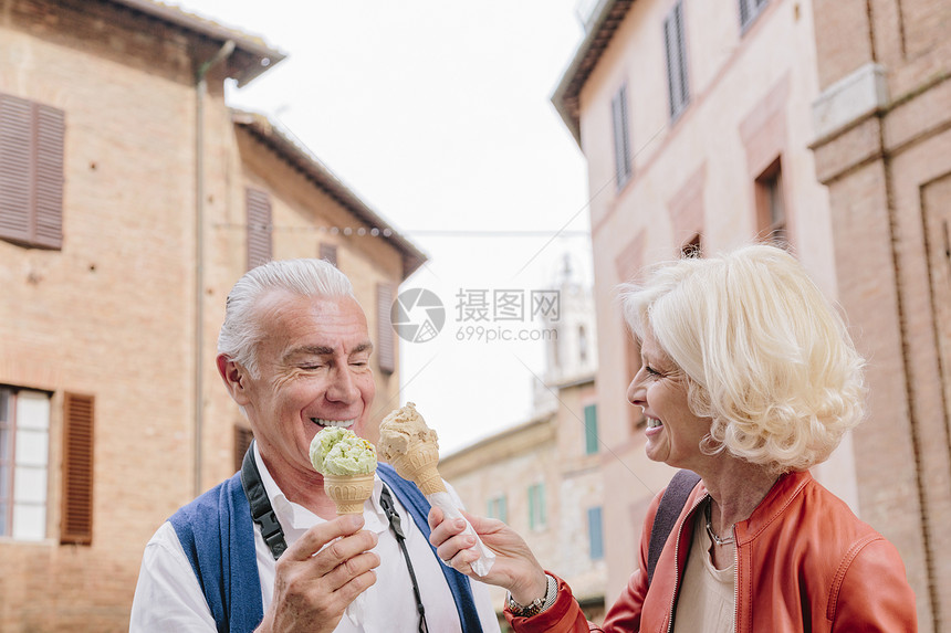 在意大利托斯卡纳州锡耶吃冰淇淋锥的旅游夫妇图片