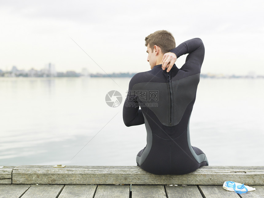 穿潜水服的男子坐在码头上图片