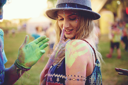 在节日上肩上有绿色手印的年轻女子和男友沾着粉末的手高清图片